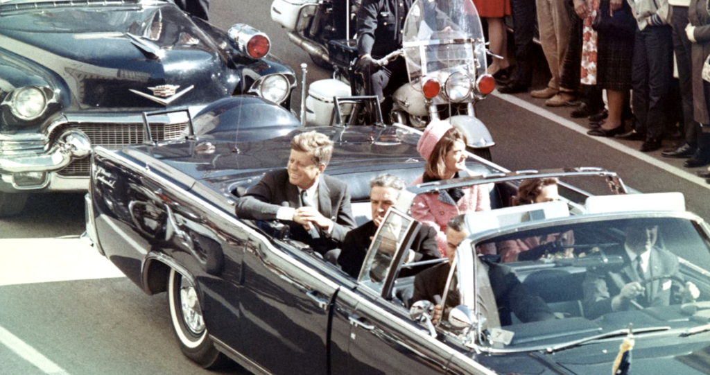 JFK rides in a motorcade moments before his assassination